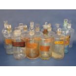 A large collection of clear glass apothecary bottles, many with original labels and stoppers (15)
