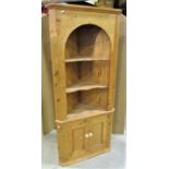 A stripped pine Georgian style freestanding corner cupboard, partially enclosed by a pair of