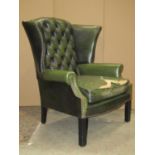 A pair of Georgian style faux green leather wing armchairs with button backs, loose squab seat