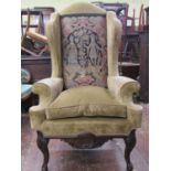 A substantial Georgian style wing chair with scrolled arms raised on a carved frame, cabriole