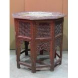 An Eastern occasional table of octagonal form with profusely carved foliate detail and inset