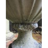 A weathered cast composition stone campana shaped garden urn with raised grape and vine detail,