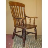 A Windsor lathe back armchair principally in beech with saddle shaped seat raised on turned supports
