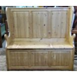 A stripped pine settle with winged and fielded panelled back over a hinged box seat with panelled