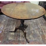 A Georgian oak snap top table the circular top 80 cm in diameter, raised on a turned pillar and