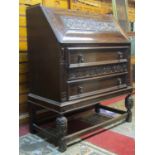 A good quality Edwardian/1920s oak Jacobean style bureau with scrolling grape and vine detail, the