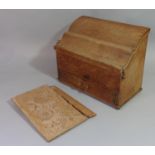 An Arts & Crafts style oak stationery box with slopping serpentine shaped hinged lid enclosing a