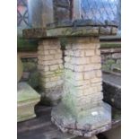 A weathered cast composition stone two sectional bird bath with simulated brick work facade,