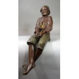 An early 20th century Austrian Goldscheider figure of a smiling bare legged boy in seated