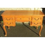 A vintage French light oak kneehole dressing table fitted with an arrangement of five frieze drawers