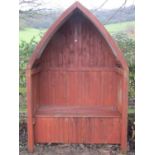 A stained pine framed garden arbour and combined hinged box seat beneath a lancet shaped canopy with