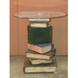 A novel contemporary occasional table in the form of a stack of old books beneath a circular glass