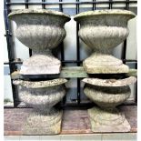 Four small matching weathered cast composition stone garden urns with lobed bodies and square cut