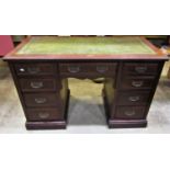 An Edwardian walnut kneehole twin pedestal writing desk with green inset panelled top over an
