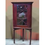A Georgian style mahogany corner cabinet enclosed by an astragal glazed panelled door, raised on a