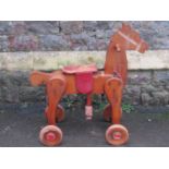 A vintage child's wooden move along rocking horse with wooden wheels