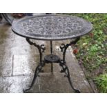 A cast aluminium garden terrace table of circular form with decorative pierced scrolling acanthus