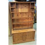 A stripped pine kitchen dresser in two sections, the low base enclosed by a pair of square fielded