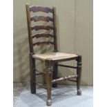 A set of four stained ashwood wavy ladderback dining chairs with rush seats raised on turned