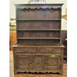 An 18th century style oak cottage dresser, the base enclosed by an arrangement of panelled doors and