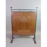 An Arts & Crafts iron framed firescreen enclosing a copper panel with embossed rose design 67 cm
