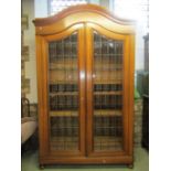 A substantial walnut bookcase with arched outline enclosed by two glazed and barred doors, the glass