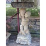 A weathered contemporary composition stone two sectional bird bath in the form of a cherub