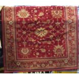 A red ground Persian style wool rug with red field and geometric floral panels within further