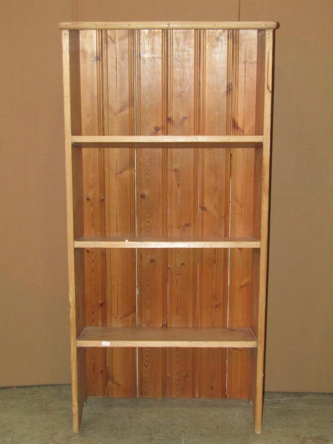 A stripped pine floorstanding shelf unit with three fixed sloping shelves, 63 cm wide x 28 cm x