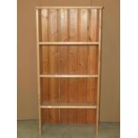 A stripped pine floorstanding shelf unit with three fixed sloping shelves, 63 cm wide x 28 cm x