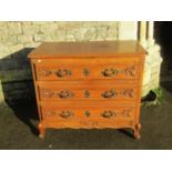 A medium to light oak commode of three long drawers with carved foliate detail and fixed cast