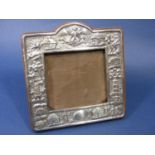 A good quality Eastern white metal easel picture frame, embossed with Buddhistic deities, village