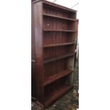 A stained pine framed freestanding open bookcase with five adjustable shelves and tongue and