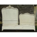 A pair of French single bedsteads with shaped and moulded outline and scrolled acanthus detail and
