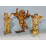 Two similar carved and painted soft wood figures of cherubs, one holding a parchment of text, the
