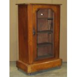 An Edwardian walnut music cabinet with inlaid detail and enclosed by a central glazed panelled