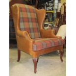 A substantial Georgian style wing armchair with shaped outline and wide generous seat partially