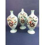 A Victorian garniture of three opaline glass baluster vases, each decorated in relief with acorn and
