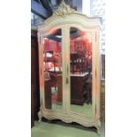 An armoire with painted finish, enclosed by a pair of full length bevelled edge mirror panel doors