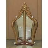 An unusual folded shield shaped corner wall mirror with gilt moulded frame and trailing foliate