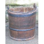 An old wooden and steel banded well bucket with loose loop handle