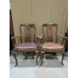 A pair of Queen Anne style walnut elbow chairs with carved vase shaped splats, with hide upholstered