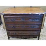 An antique oak commode of three long drawers with carved foliate detail over a shaped apron and