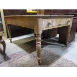A Victorian stripped pine farmhouse kitchen table of rectangular form fitted with an end frieze