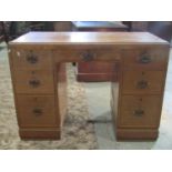 A light oak kneehole twin pedestal desk/dressing table fitted with an arrangement of seven frieze