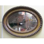 Early 20th century wall mirror of oval form, the deeply moulded frame with repeating geometric