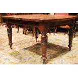A late Victorian mahogany extending dining table raised on four turned, tapered and carved supports,