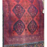 A Persian wool carpet with red ground, multi medallion panels in a black colourway within