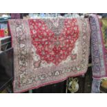 A large red ground Persian style wool carpet with abstract floral detail within several running