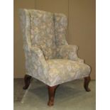 A Georgian style wing armchair with shaped outline and green ground floral patterned upholstery